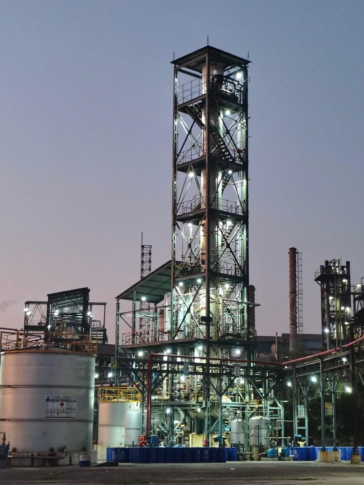 Illuminated manufacturing process tower and plant equipment at dusk